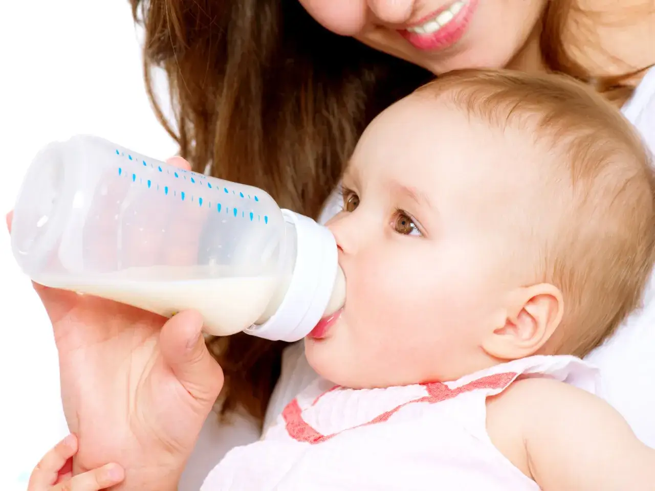 Bambino beve latte vaccino da biberon, nutrito da una madre sorridente.