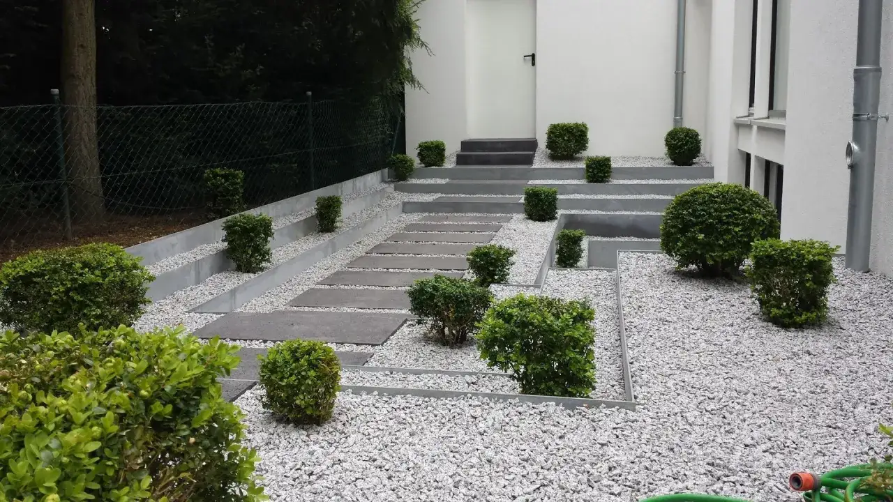 Moderner Vorgarten gestalten mit Stufen, Kies und Buchsbaumkugeln. Ein Weg aus Betonplatten f&uuml;hrt zur Haust&uuml;r.