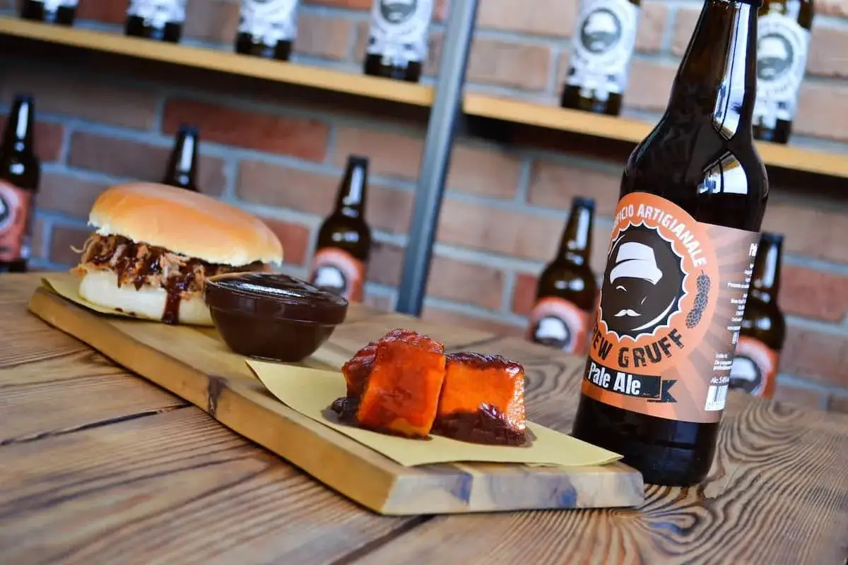 Un panino pulled pork, salsa barbecue e due cubetti di carne glassata, accompagnati da una birra artigianale del birrificio Mastro Matto.
