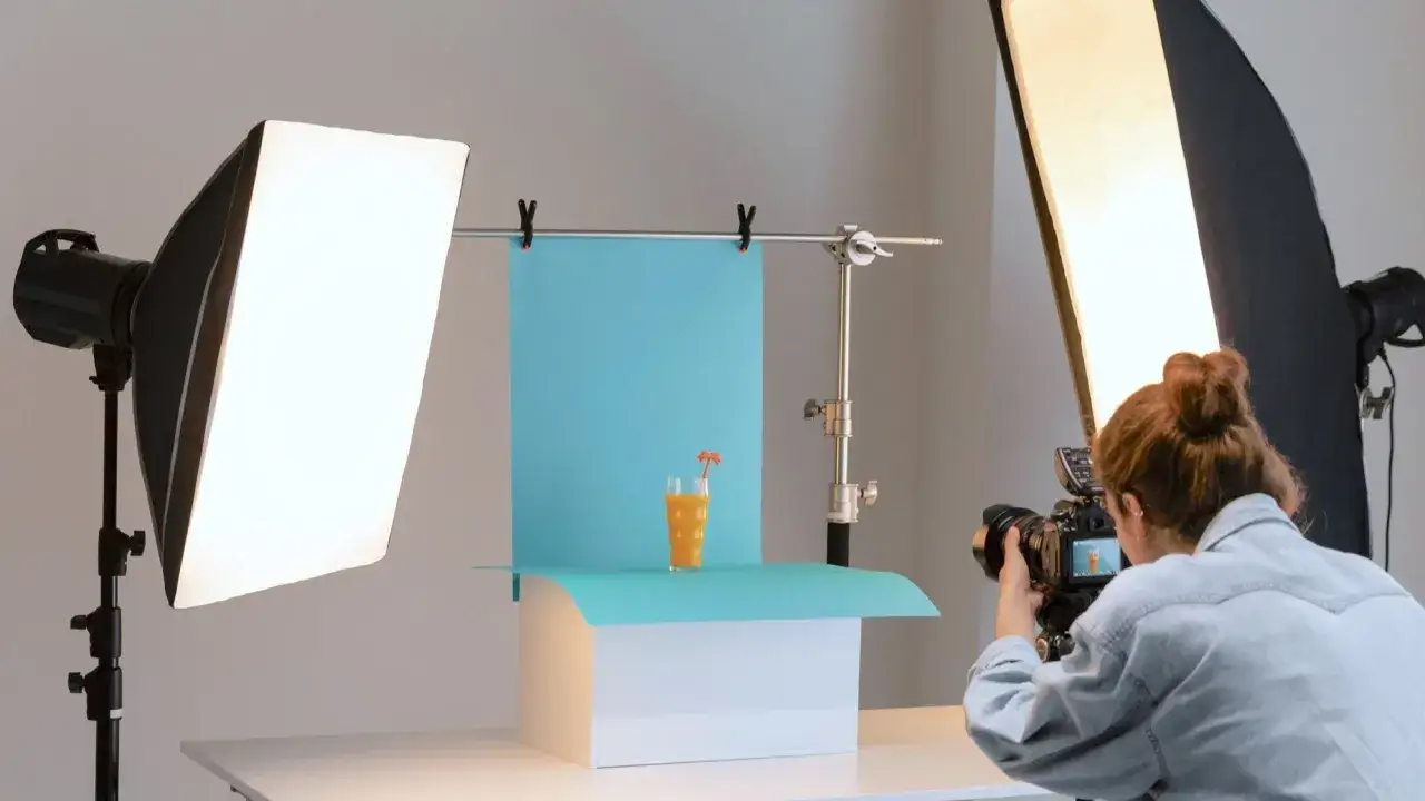 Profesjonalna fotografia produktowa: ustawienia aparatu, oświetlenie i szklanka soku pomarańczowego na niebieskim tle.