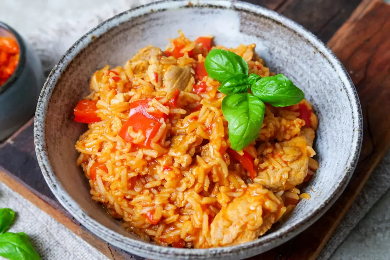 Herzhaftes serbisches Reisfleisch mit Paprika und Basilikum in einer rustikalen Schüssel, bereit zum Genießen.