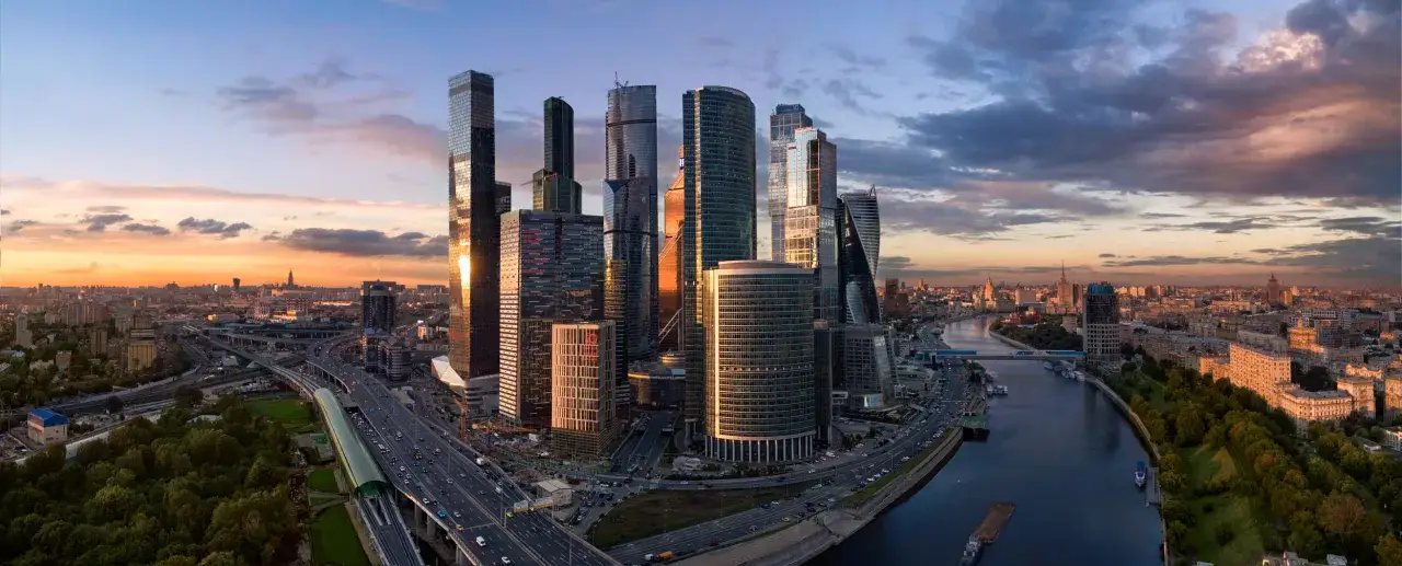 Wieżowce Moscow City o zachodzie słońca, niczym oko Moskwy, lśnią w promieniach, a ruchliwe autostrady i rzeka tworzą tętniące życiem tło.