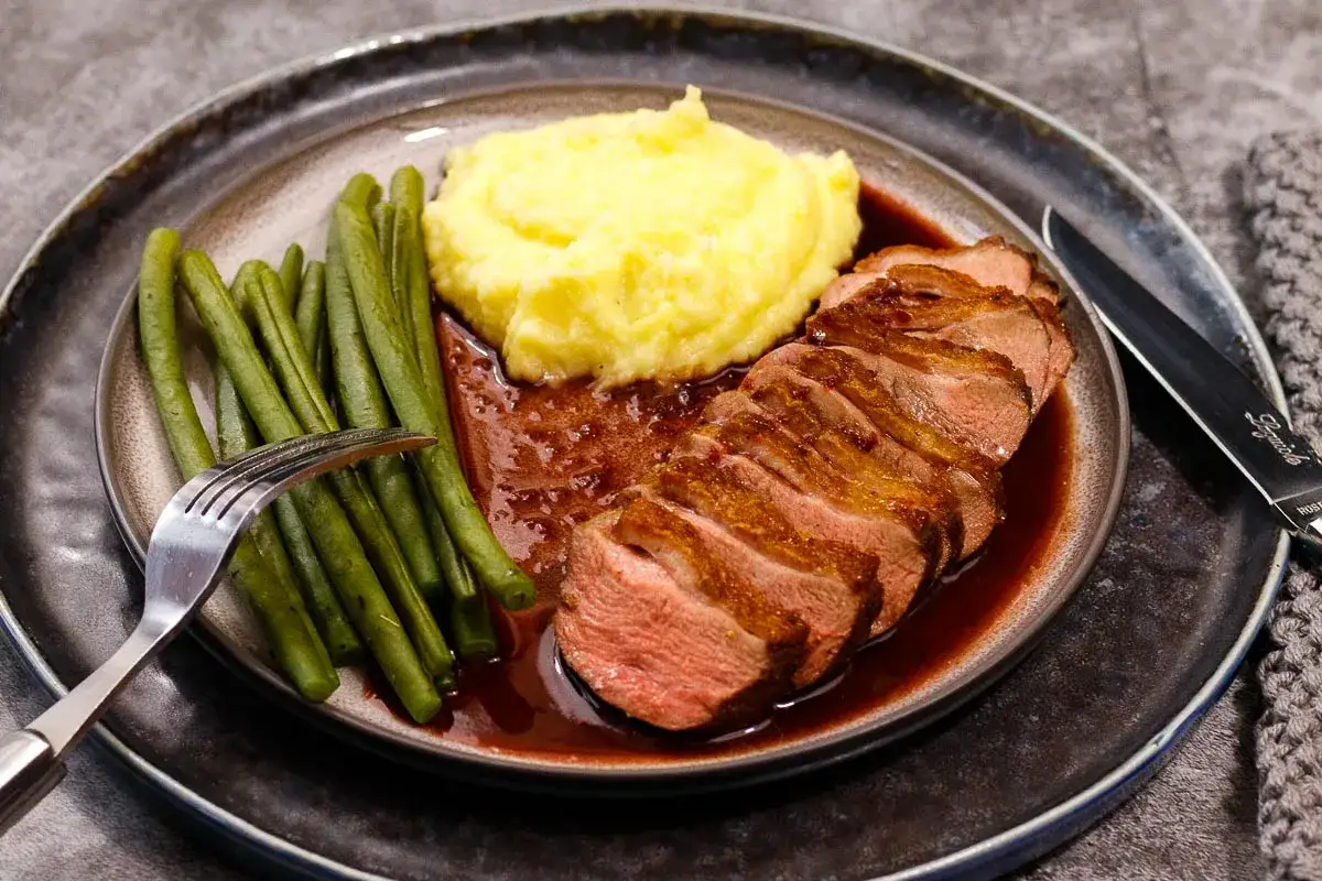 Gegrillte Entenbrust mit Kartoffelpüree, grünen Bohnen und einer Sauce, verfeinert mit Portwein zum Kochen.