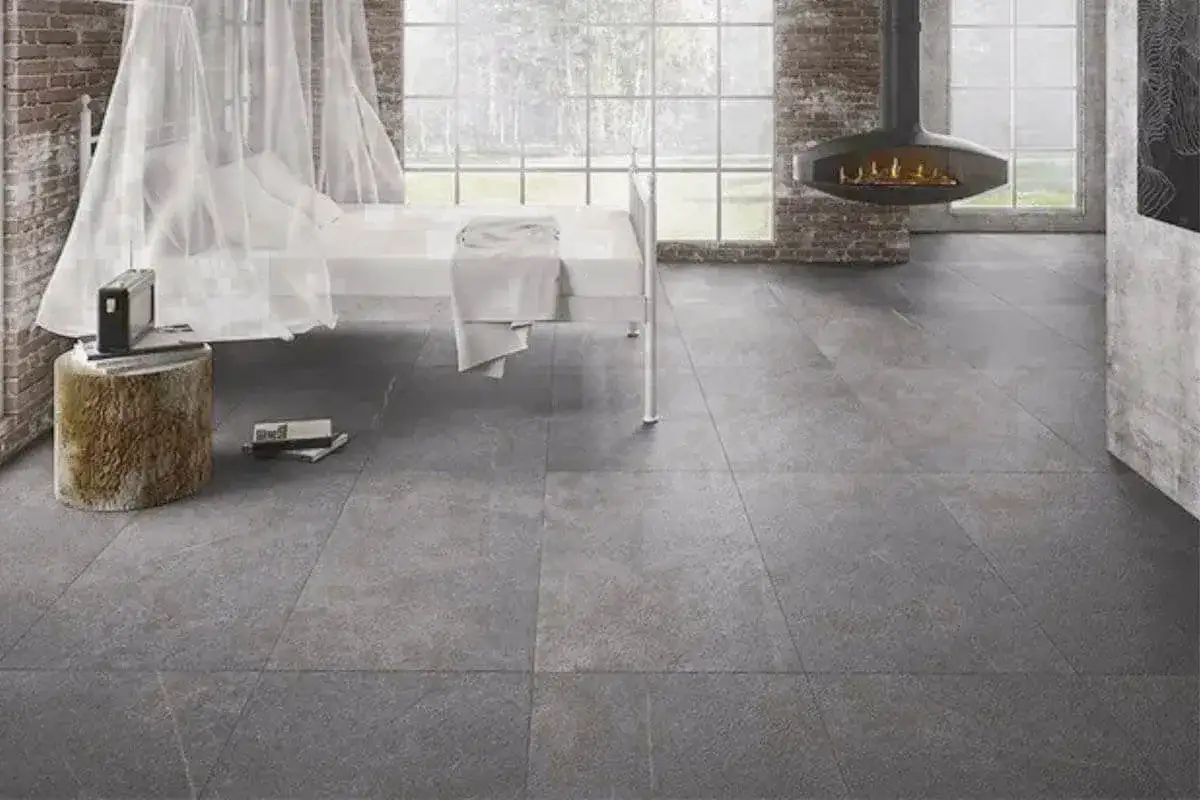 Un letto bianco con zanzariera, un camino sospeso e un pavimento in grès effetto pietra naturale.