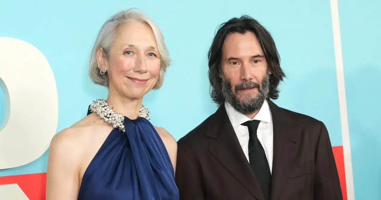 Keanu Reeves z żoną Alexandrą Grant na tle błękitnej ściany.