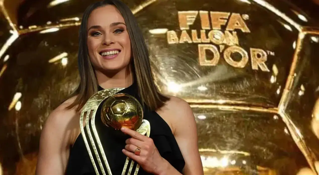 Piłkarka z uśmiechem trzyma złotą piłkę, symbol swojego triumfu. W tle błyszczy wielka złota piłka z napisem FIFA Ballon d'Or.