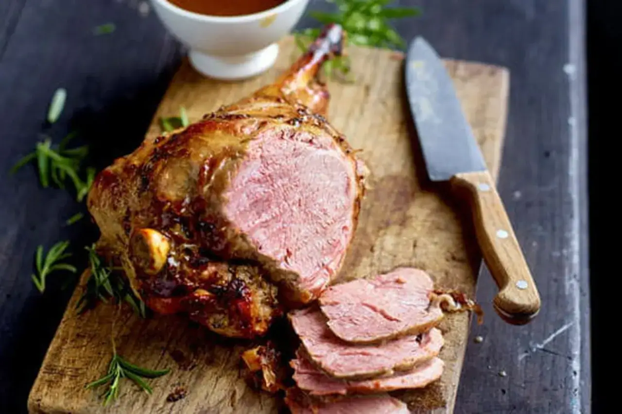 Gigot d'agneau rôti, juteux et rosé, prêt à être dégusté. Une recette parfaite pour un repas de fête.