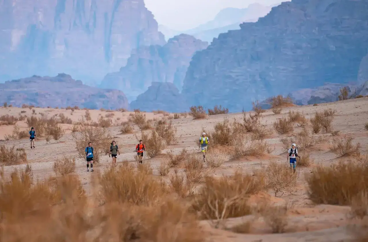L&auml;ufer k&auml;mpfen sich durch die W&uuml;ste, ein harter Wettkampf wie der Badwater 135. Berge im Hintergrund.