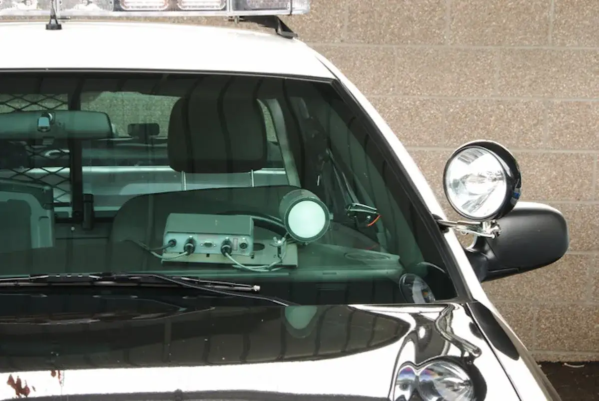 Int&eacute;rieur d'une voiture de police banalis&eacute;e, avec un radar discret sur le tableau de bord, pr&ecirc;t &agrave; flasher.