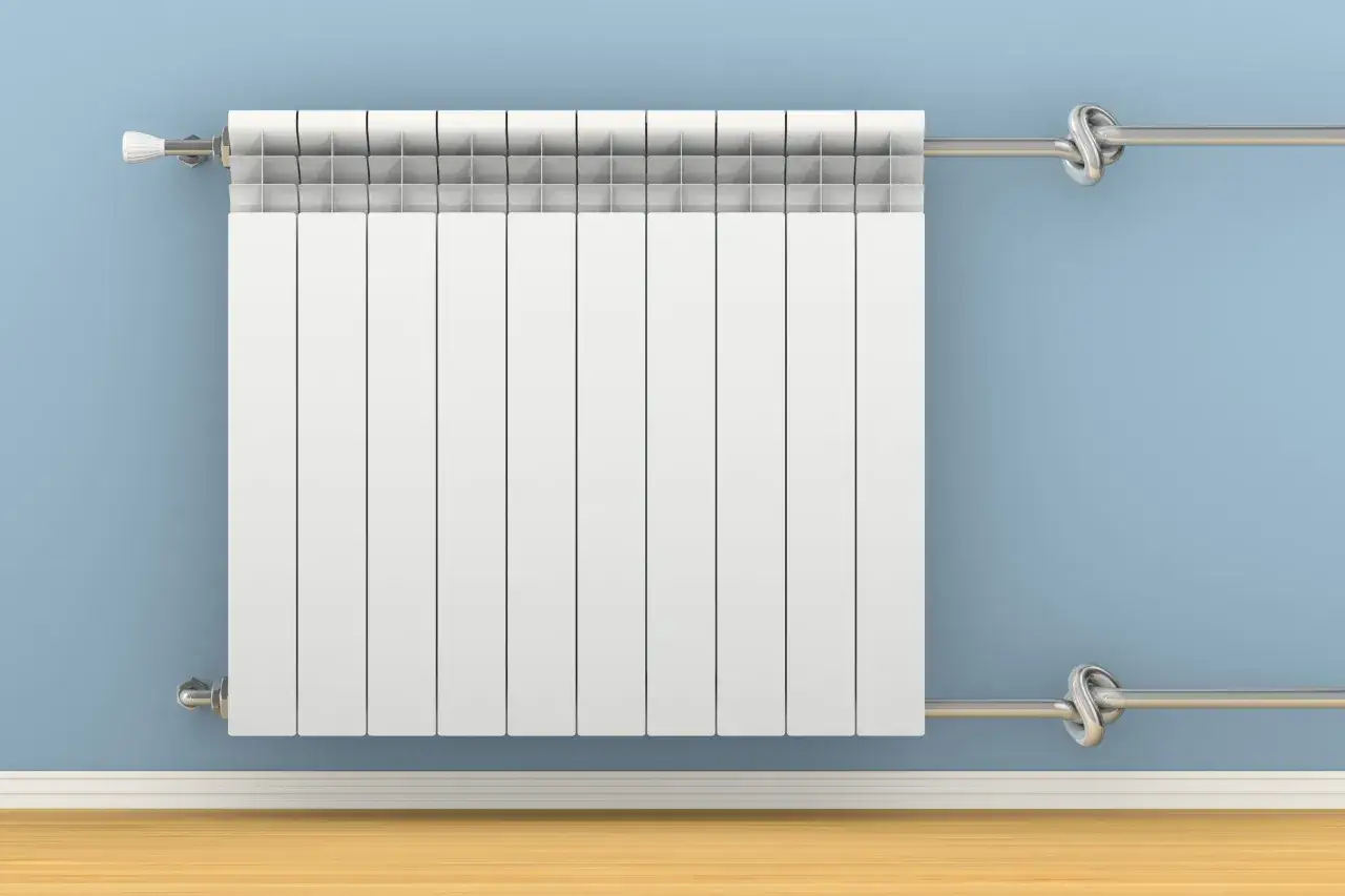 Radiateur blanc moderne sur mur bleu, avec tuyaux argentés pour le branchement radiateur eau.
