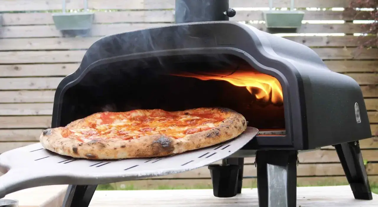 Gorąca pizza napoletana z serem i sosem pomidorowym na łopacie, gotowa do wyjęcia z pieca opalanego drewnem.