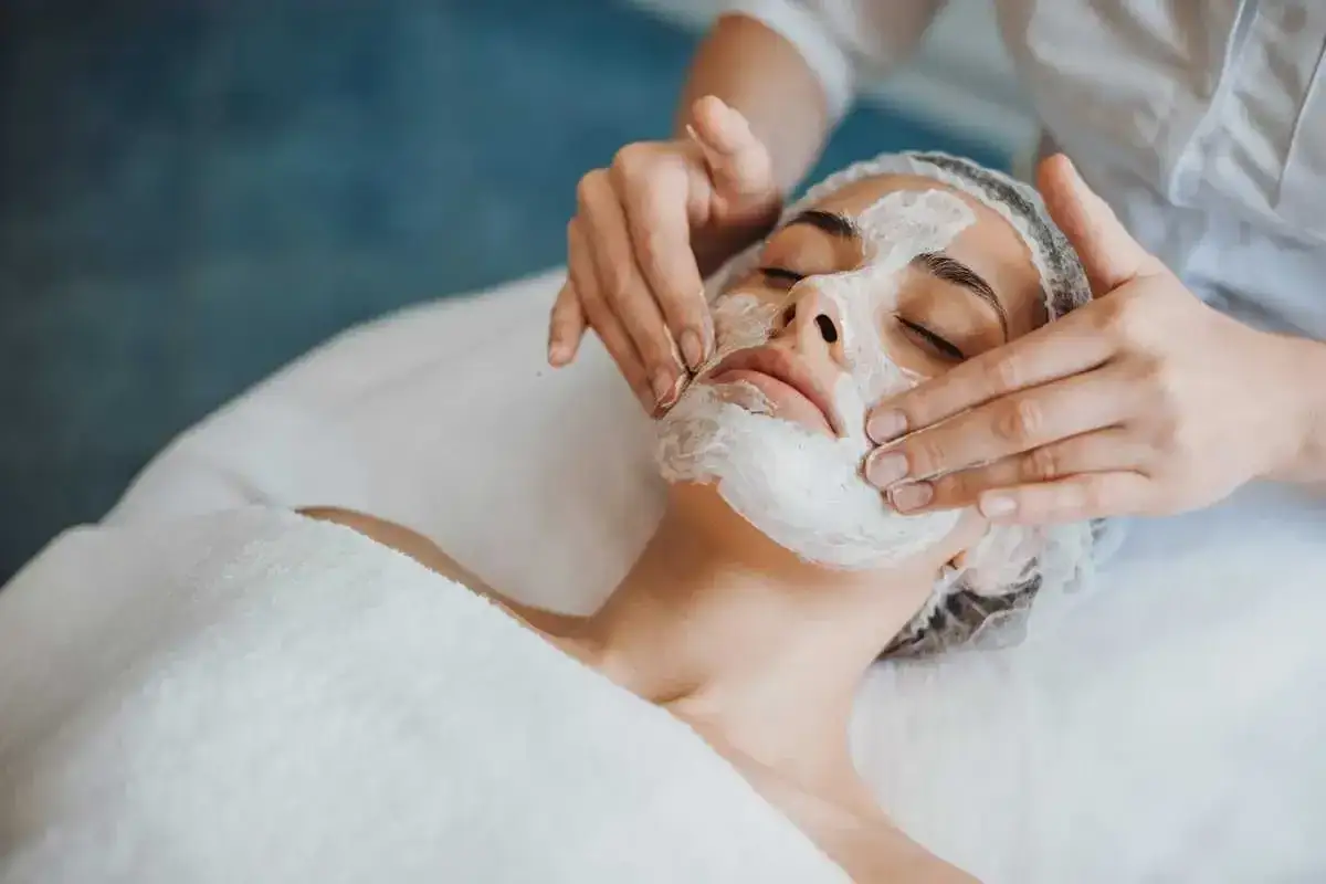 Mani esperte applicano una maschera idratante per un trattamento estetico viso rigenerante.