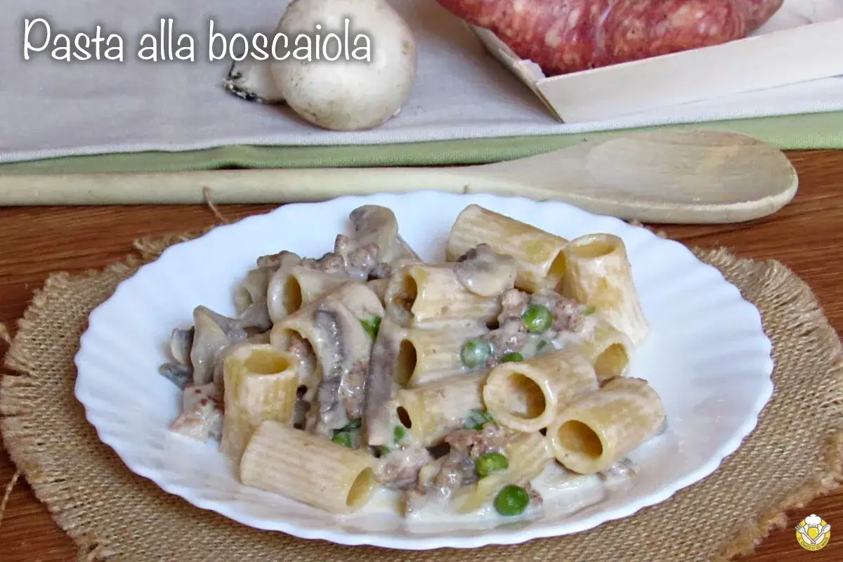 Piatto di pasta alla boscaiola con funghi, piselli e salsiccia, servita su un piatto bianco.