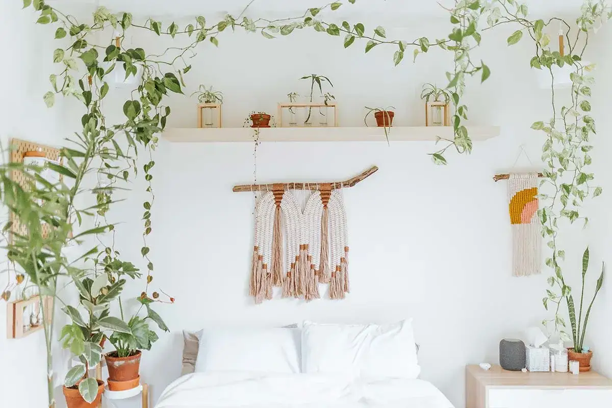 Ideas para decorar habitación: plantas colgantes, macramé y estantería con macetas crean un ambiente natural y acogedor.