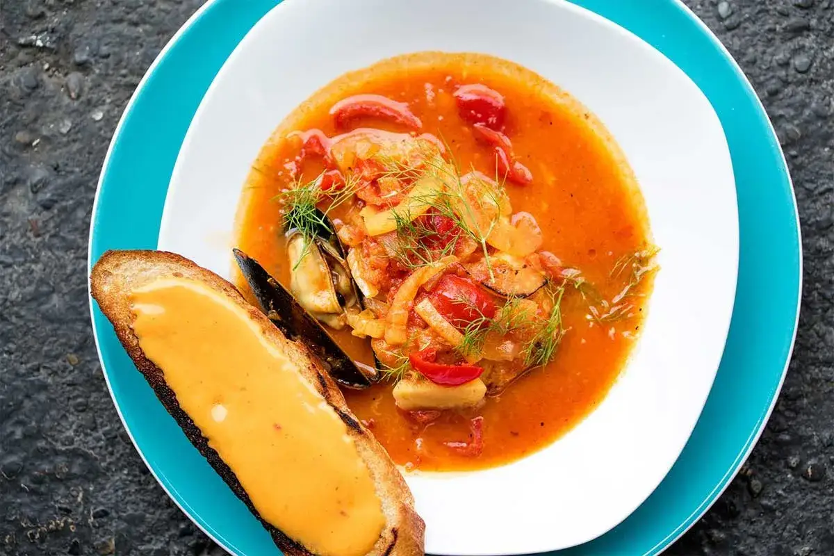 En smakrik bouillabaisse med musslor och tomat, serverad med rostat br&ouml;d med en kr&auml;mig topping. Perfekt vin till bouillabaisse!