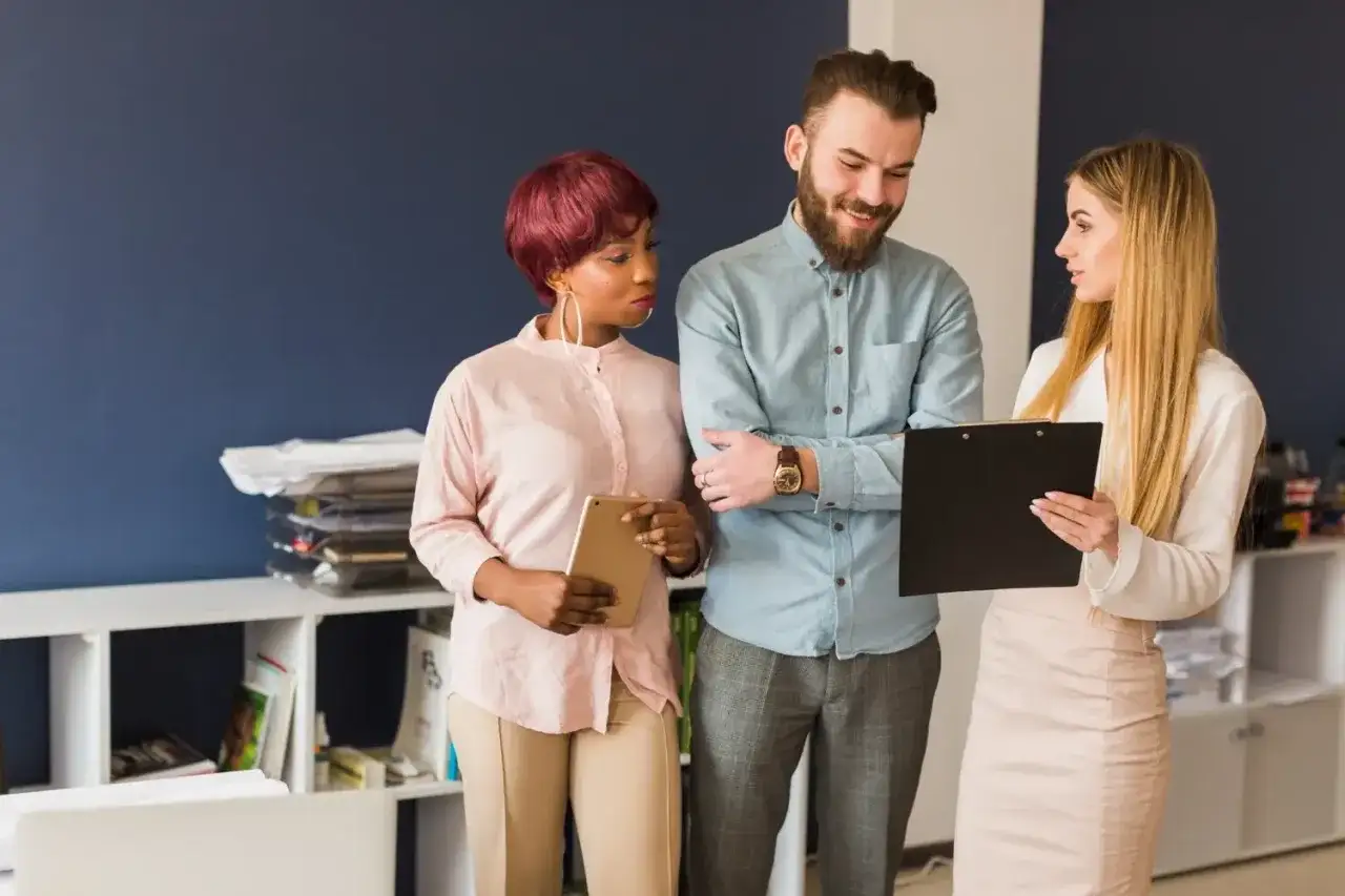 Key account manager omawia projekt z zespołem. Kobieta z tabletem i mężczyzna z teczką dyskutują.