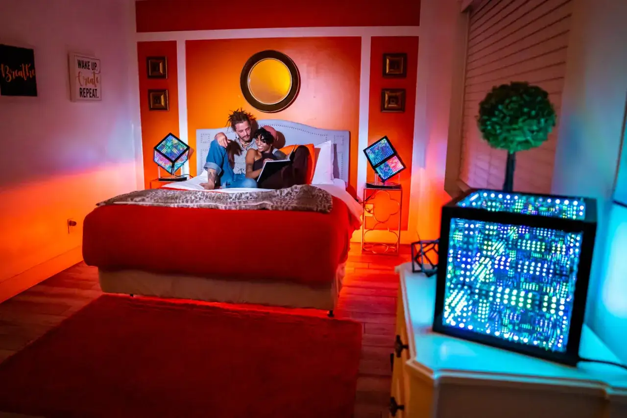 Pareja en cama rodeada de un **espectro luz led** que crea un ambiente vibrante.