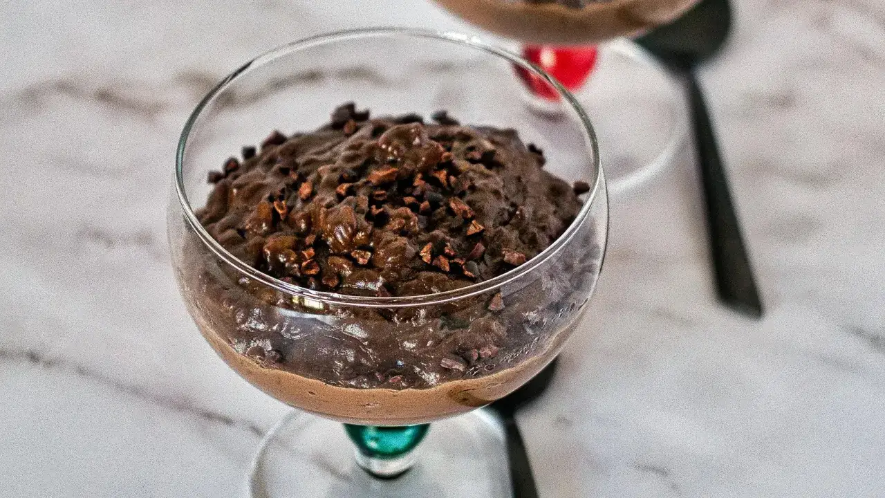Un délicieux riz au lait au chocolat, garni de grué de cacao, servi dans un verre élégant.