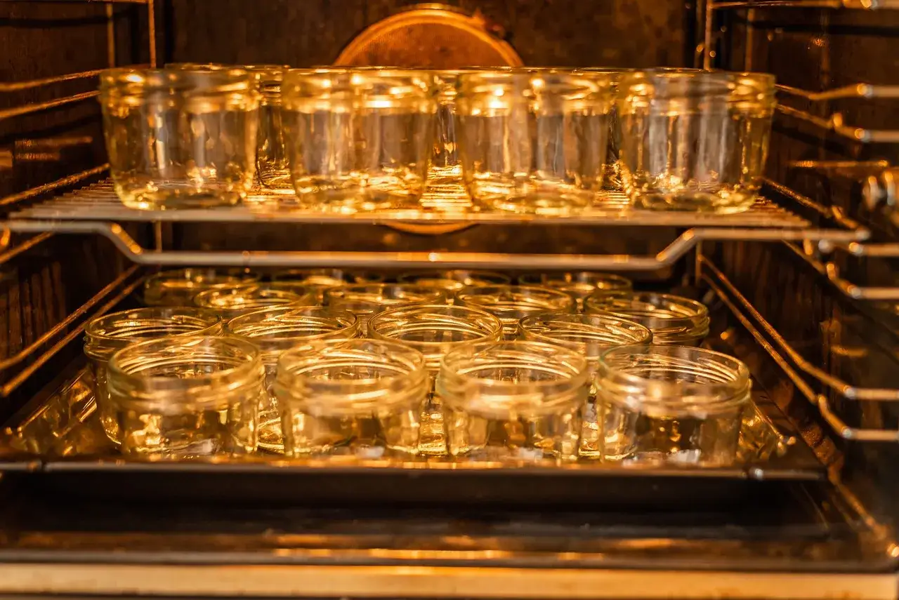 Viele leere Gl&auml;ser stehen auf zwei Ebenen im Ofen, bereit zum Einkochen. Ein kleiner Fehler beim Sterilisieren k&ouml;nnte den ganzen Aufwand zunichte machen.