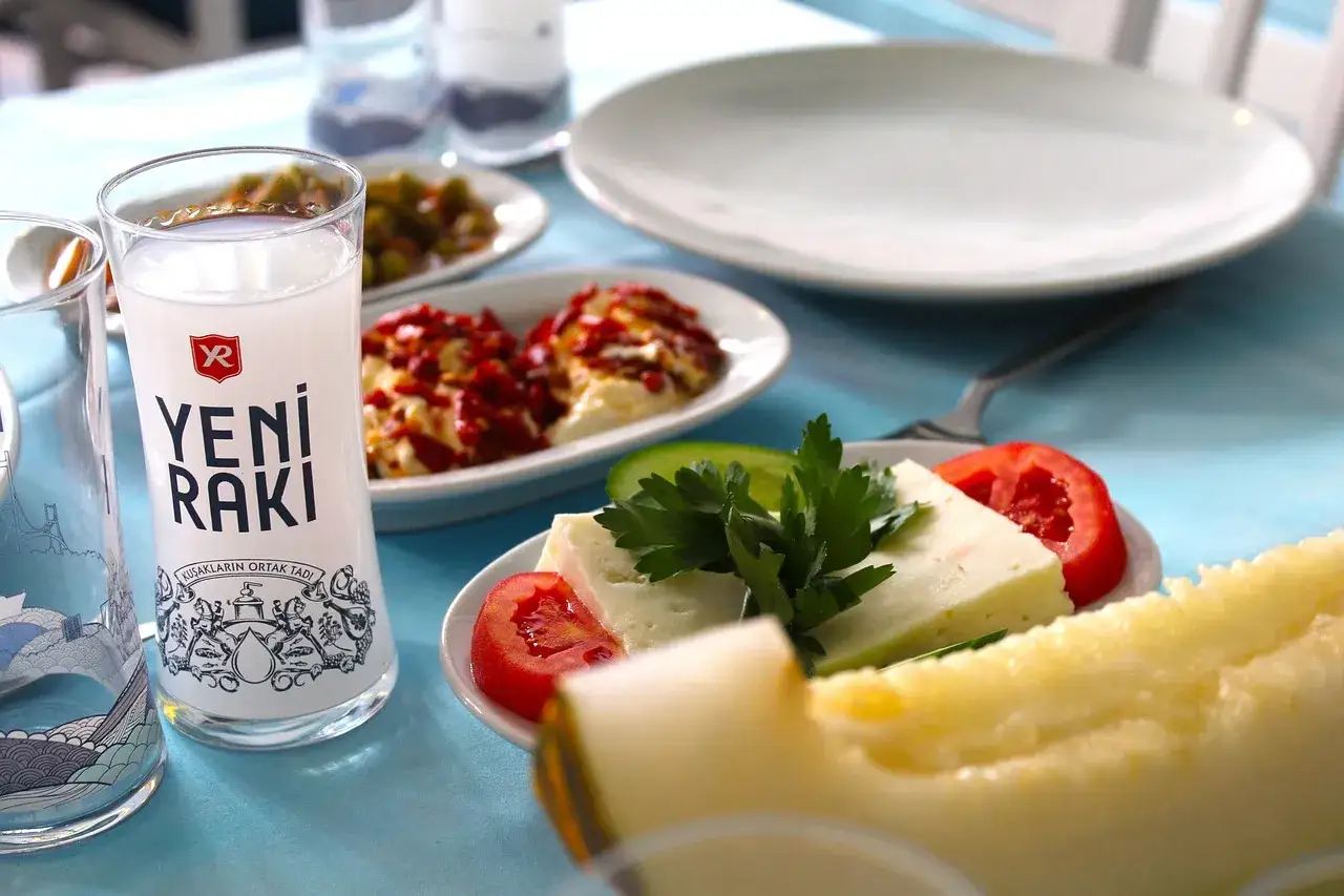 Szklanka Yeni Raki, ser, pomidory, ogórek i melon tworzą apetyczny zestaw.