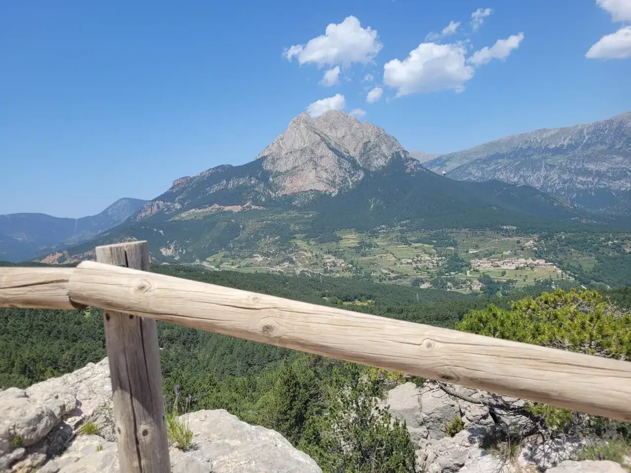 Vista panor&aacute;mica de los cingles de Vallcebre, con un gran pico monta&ntilde;oso al fondo y un pueblo en el valle.