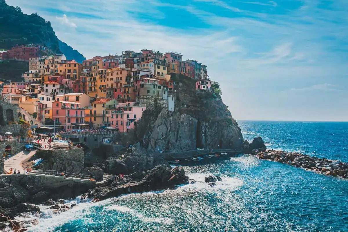 Pueblo costero italiano con casas coloridas en un acantilado. Ideal para excursiones desde Milán.