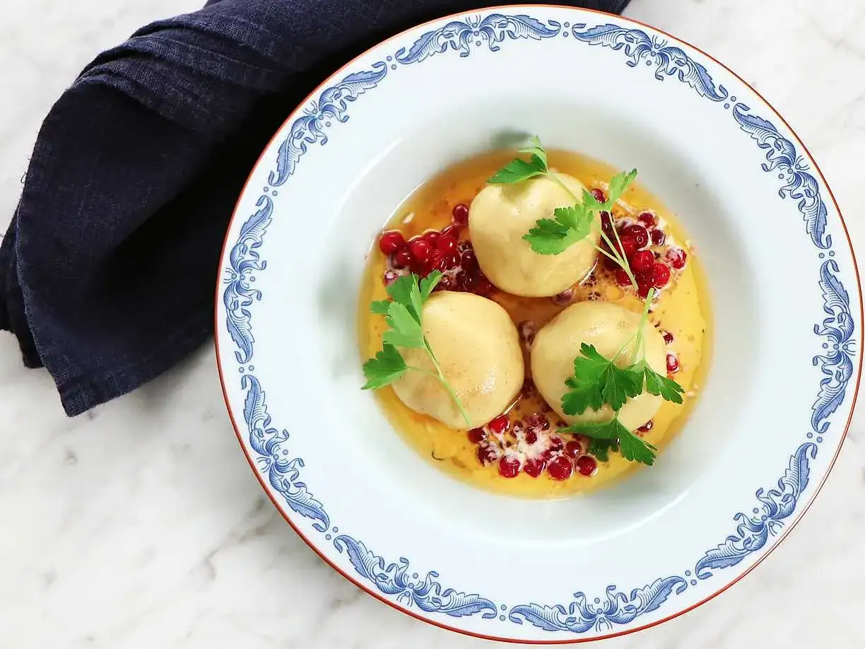 Tre gyllene kroppkakor i en sk&aring;l med lingon och persilja. Ett vackert recept p&aring; kroppkakor som ser uts&ouml;kt ut.
