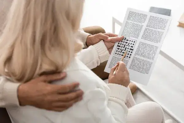 kobieta rozwiązująca krzyżówkę, ołówek, gazeta
