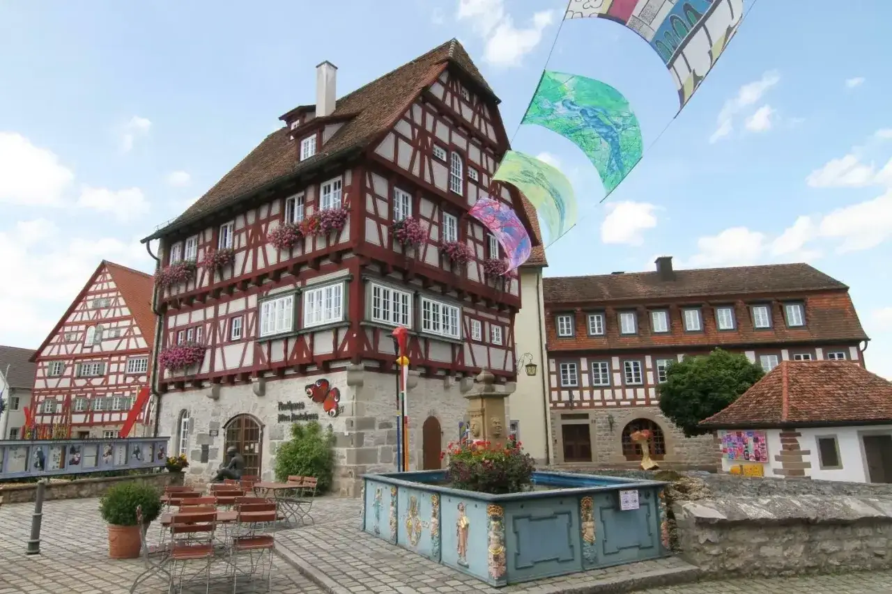 Fachwerkhäuser am Marktplatz in Vellberg, wo bald der Weihnachtsmarkt stattfindet. Bunte Fahnen wehen im Wind.