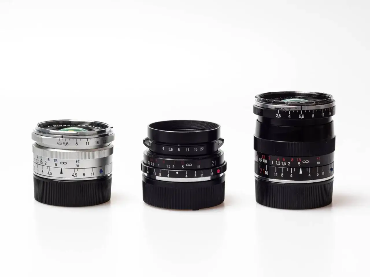 Three vintage M-mount camera lenses, including a silver Biogon, are displayed, showcasing some of the best M mount lenses for photographers.