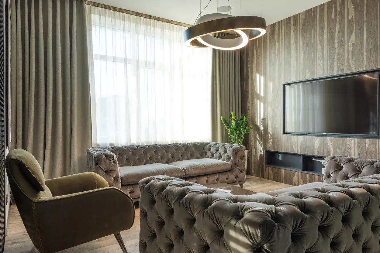 Elegancki salon z kanapami Chesterfield i podwójnym karniszem z firanami, tworzącymi przytulną atmosferę.