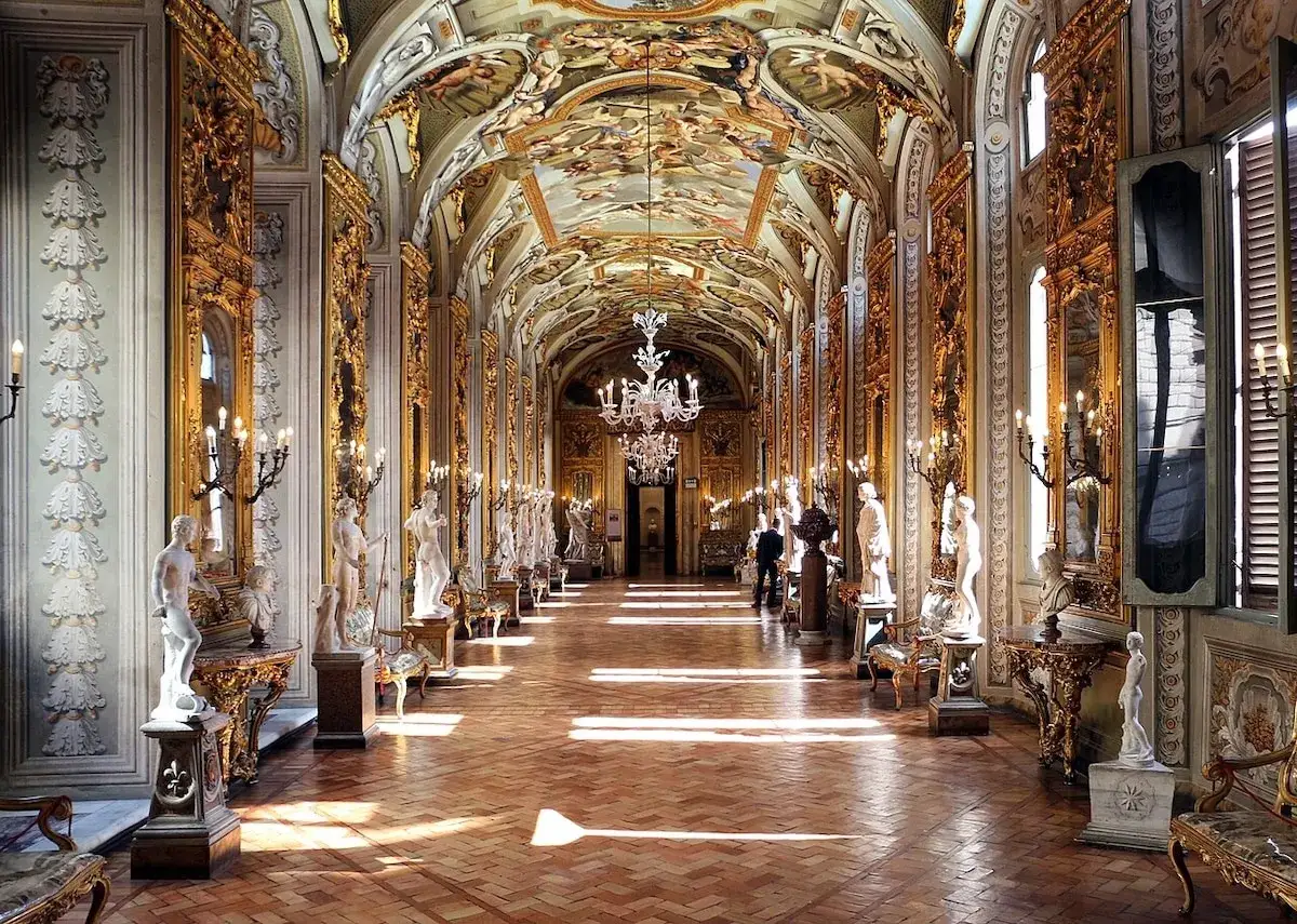 Le **Palazzo Doria Pamphilj**, un couloir orn&eacute; de statues, de dorures et de fresques au plafond, baign&eacute; de lumi&egrave;re.