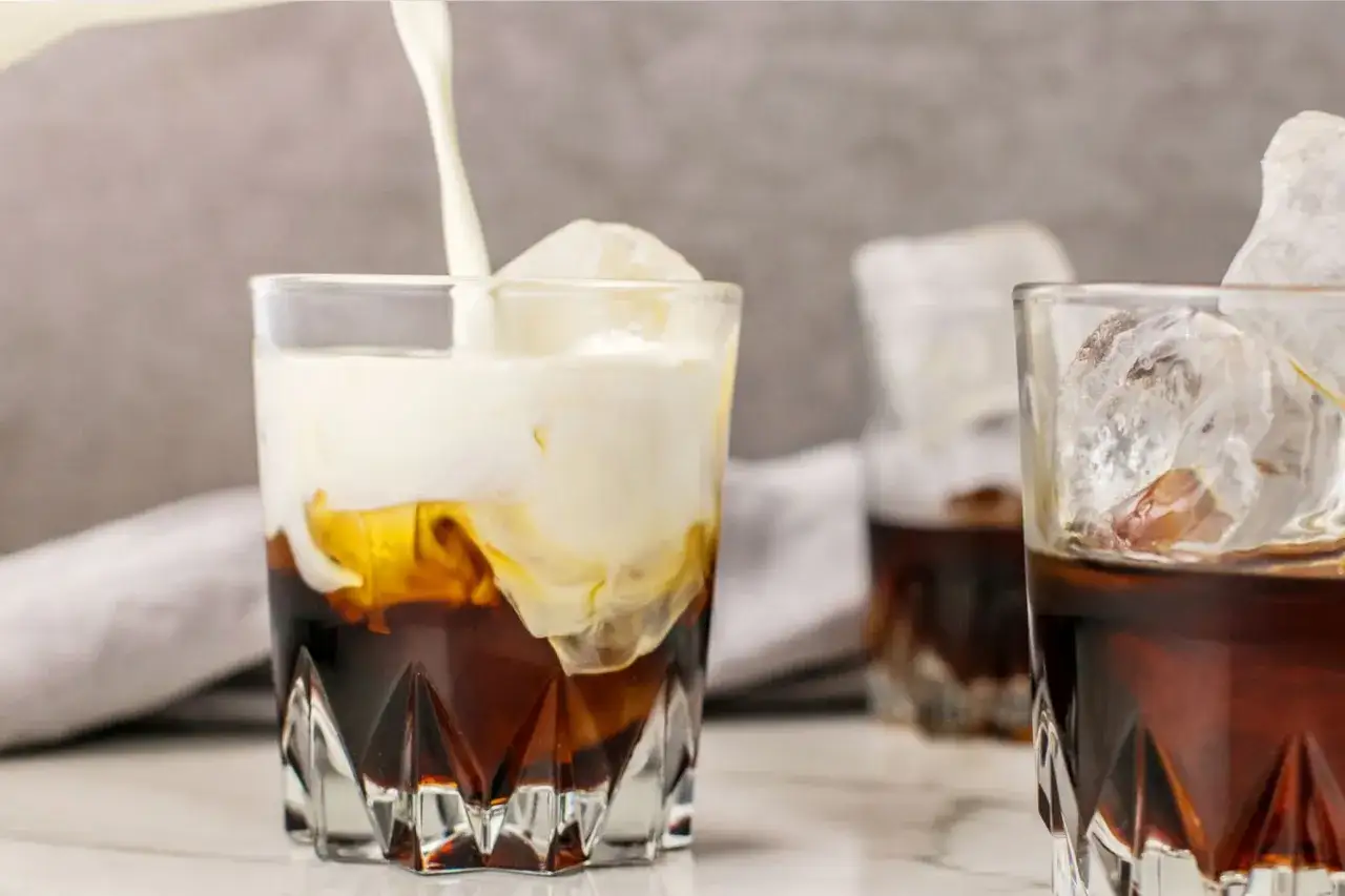 Sahne fließt in einen eisgekühlten Kaffee. Ein Genuss wie