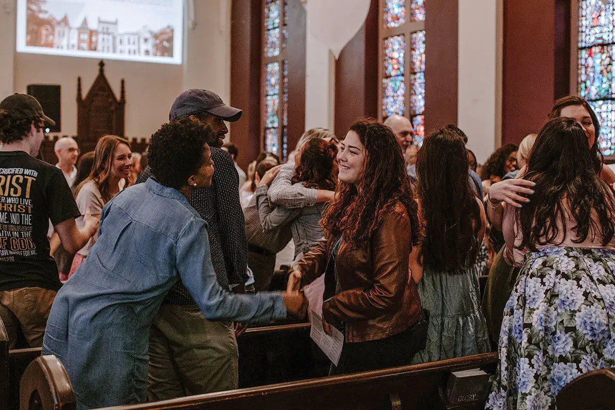 People greet each other warmly in a church, a scene that embodies the spirit of evangelism through fellowship and shared faith.