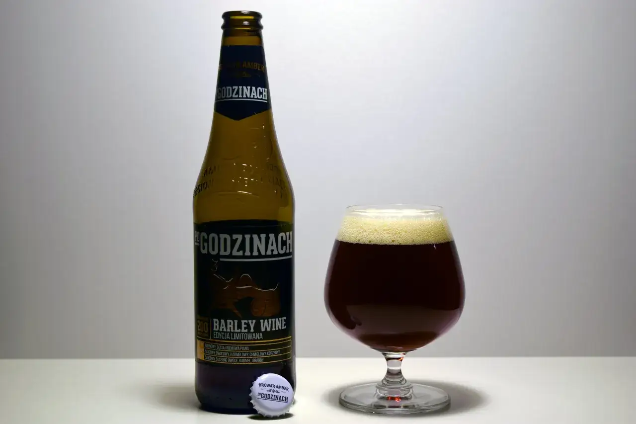 Butelka i kielich z ciemnym piwem typu barley wine. Etykieta