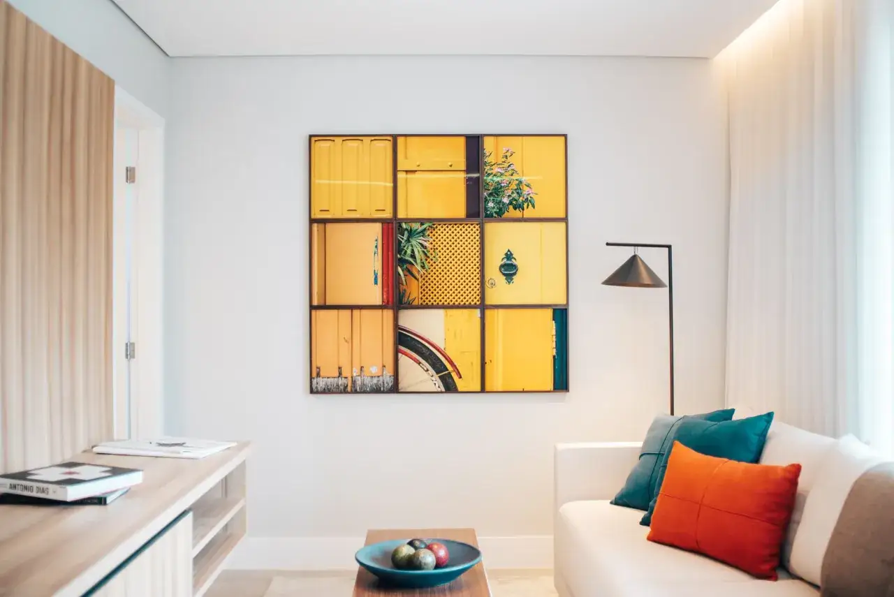 Un collage de puertas amarillas, quiz&aacute;s el cuadro m&aacute;s caro del mundo, decora una pared. A su lado, un sof&aacute; blanco con cojines coloridos.