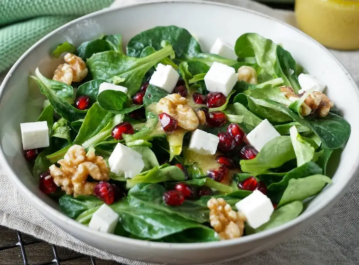 Feldsalat mit würzigem Käse, knackigen Walnüssen und saftigen Granatapfelkernen, beträufelt mit einem leichten Dressing.