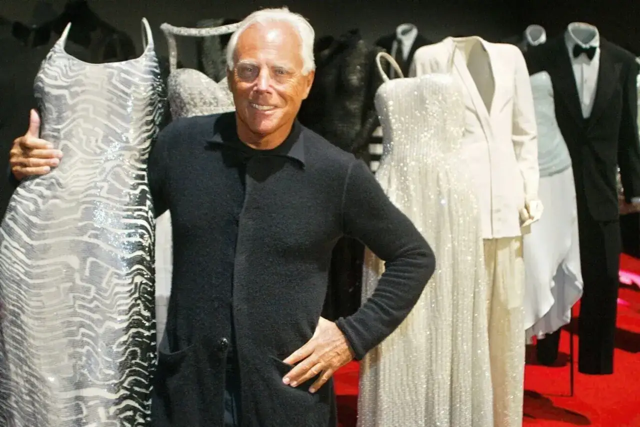 Giorgio Armani posa con abiti da sera scintillanti, esempi di marche costose che definiscono l'alta moda.