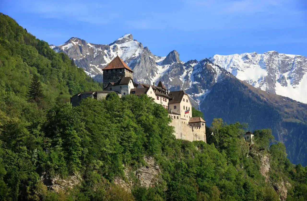 Zamek Gutenberg, symbol państwa Liechtenstein, wznosi się na zielonym wzgórzu, a w tle majestatyczne, ośnieżone szczyty Alp.