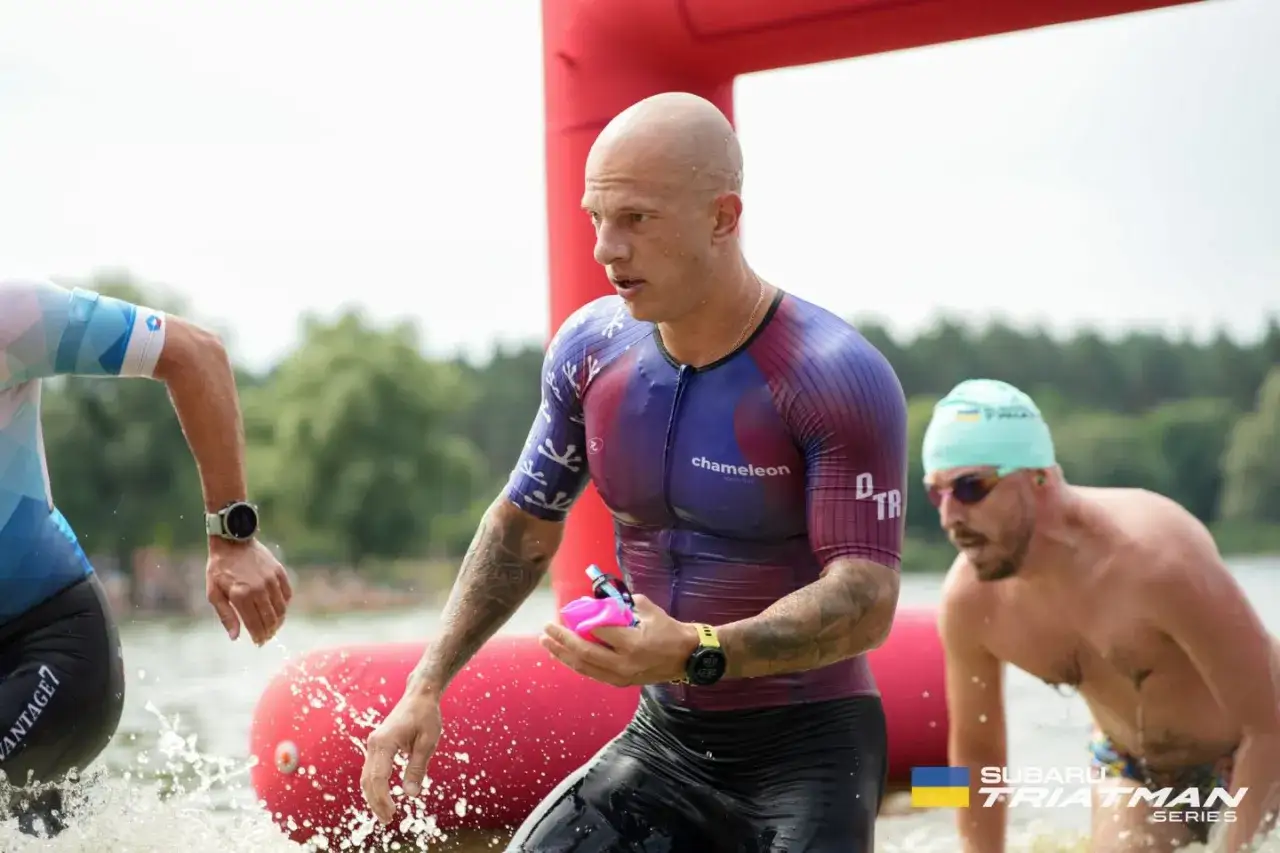 Triathleten im Wasser, die ihr Lungenvolumen trainieren. Der Mann im Vordergrund tr&auml;gt einen bunten Anzug und h&auml;lt eine pinke Trinkflasche.
