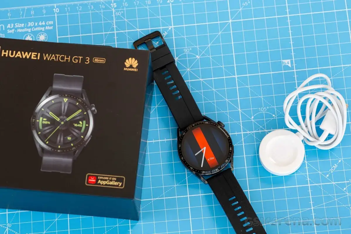 Zestaw Huawei Watch GT 3 46mm: zegarek, pudełko i ładowarka. Stylowy gadżet na niebieskiej macie.