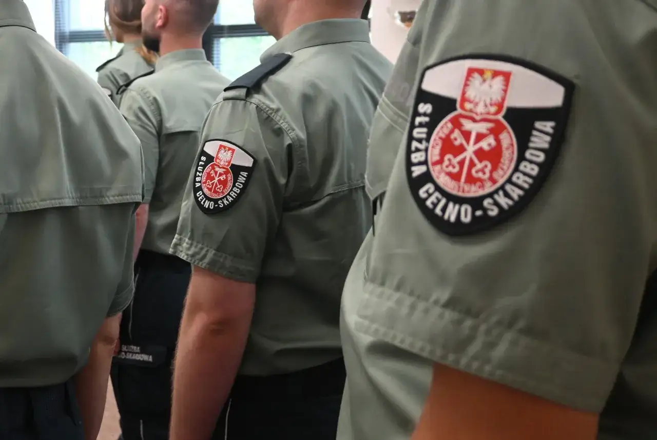 Ubrani w mundury funkcjonariusze Służby Celno-Skarbowej, z widocznymi emblematami. Ich zarobki są tematem dyskusji.