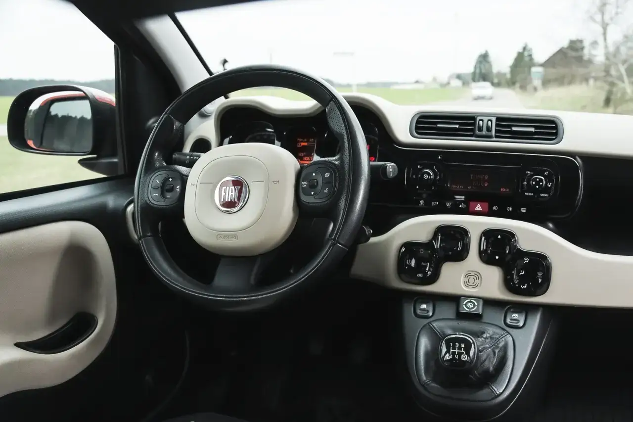 Wnętrze Fiata Panda 3: kierownica z logo FIAT, radio, dźwignia biegów i panel sterowania.