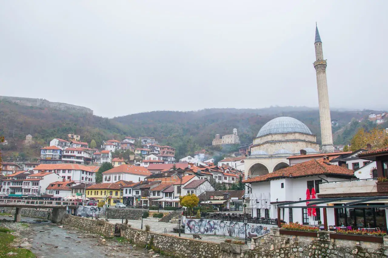 Widok na miasto z meczetem i minaretem, wzgórzem z twierdzą w tle. Kosowo atrakcje turystyczne.