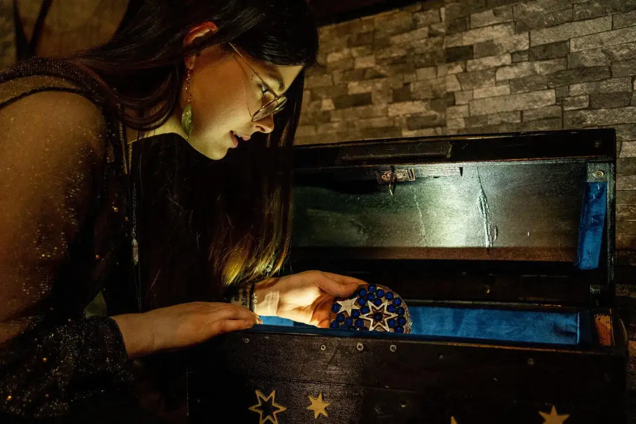 Odkrywanie tajemnic w muzeum Harry Potter Kraków. Dziewczyna z fascynacją ogląda ozdobny przedmiot ze skrzyń.