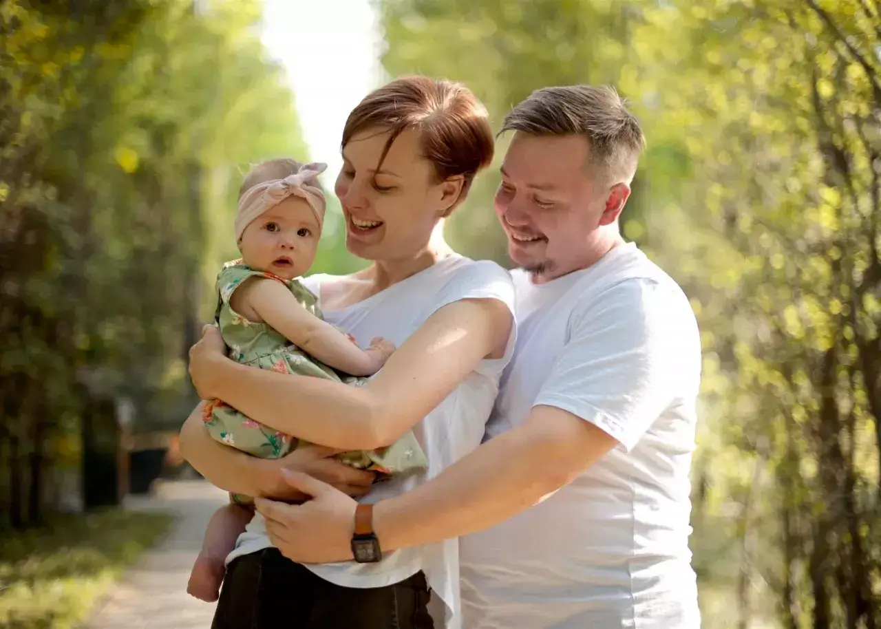 Szczęśliwa rodzina na spacerze. Mama tuli córeczkę, tata obejmuje ich. Zastanawiamy się, babciowe ile wynosi, by kupić więcej takich radosnych chwil.