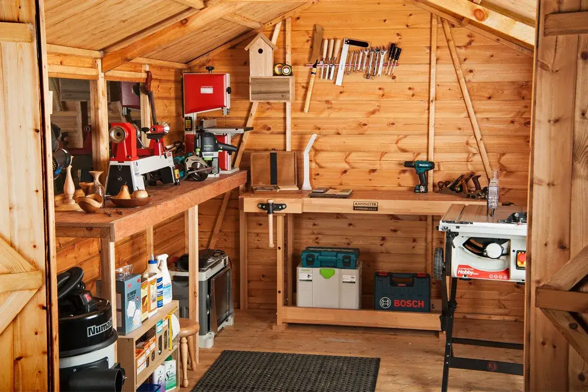 Atelier de menuiserie bien équipé avec tour à bois, scie à ruban, perceuse et divers outils à main.