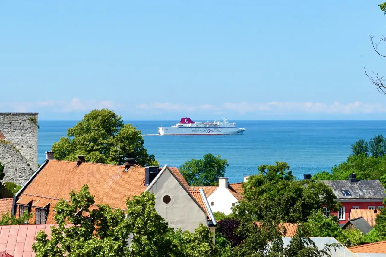 Prom płynie po morzu w kierunku Gotlandii, mijając urokliwe domy z czerwonymi dachami.