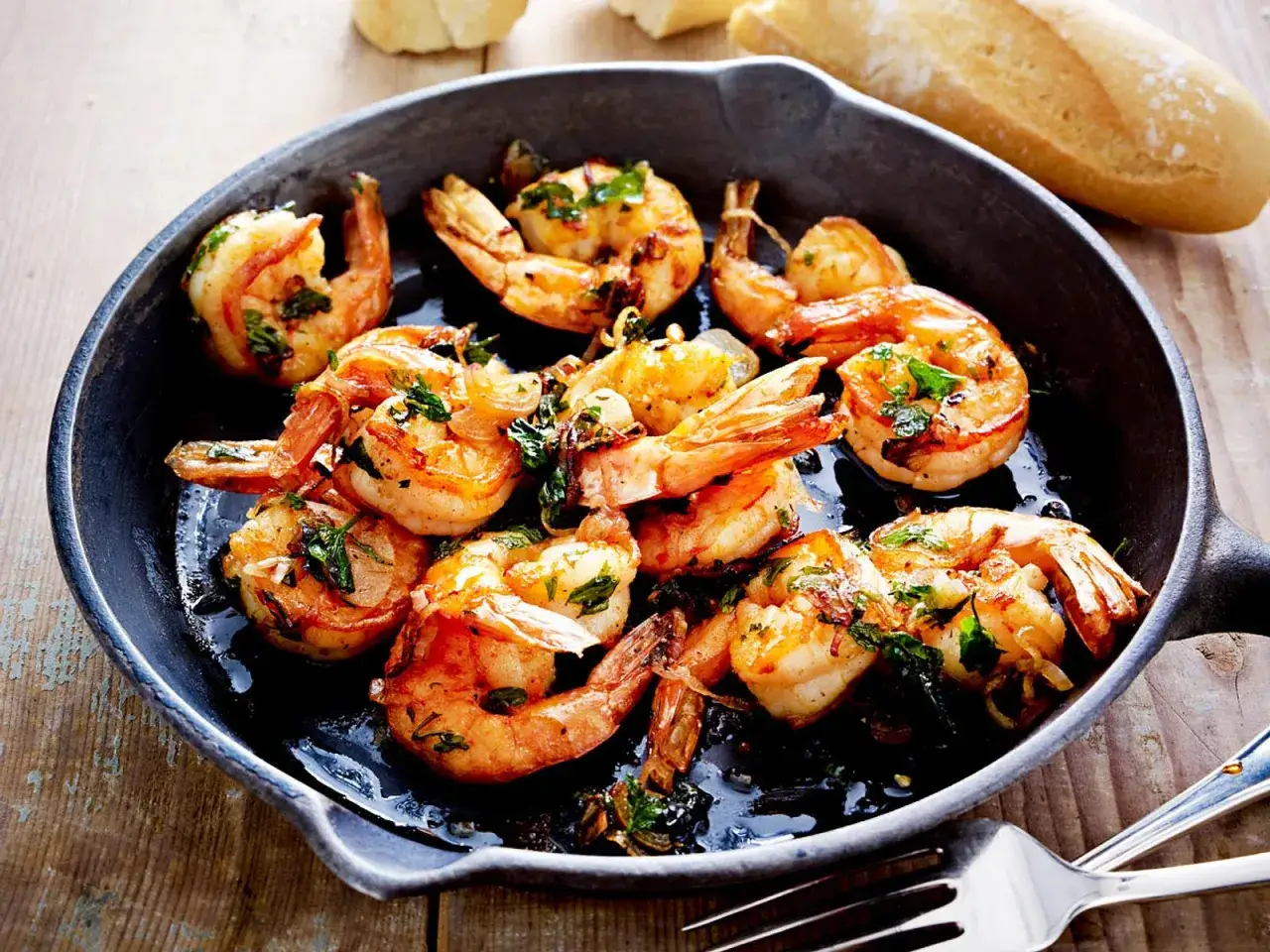 Gebratene Garnelen in einer Pfanne, ein köstliches Beispiel für Scampi Rezepte, garniert mit Kräutern.