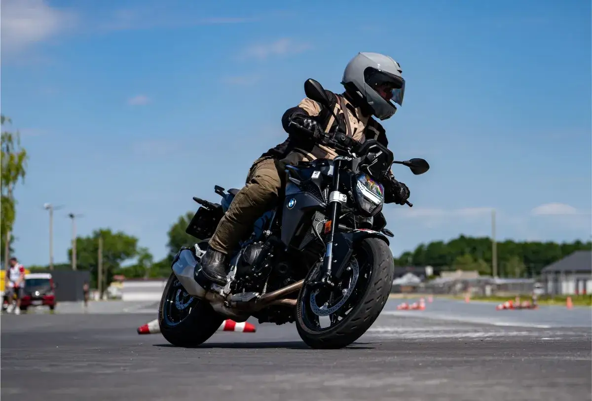 Motocyklista w kasku i stroju zręcznie manewruje na czarnym motocyklu BMW F900R, pokonując zakręt na torze.